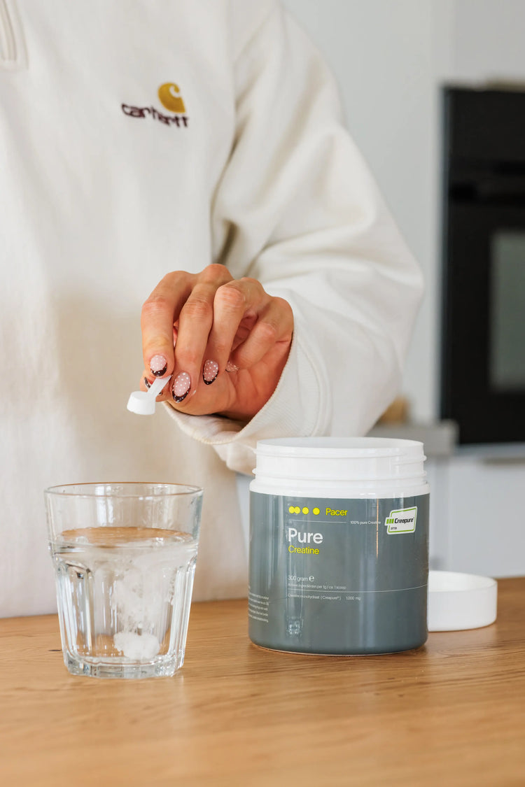 Een schepje PACER PURE creatine (Creapure®) wordt gemengd met water in een glas