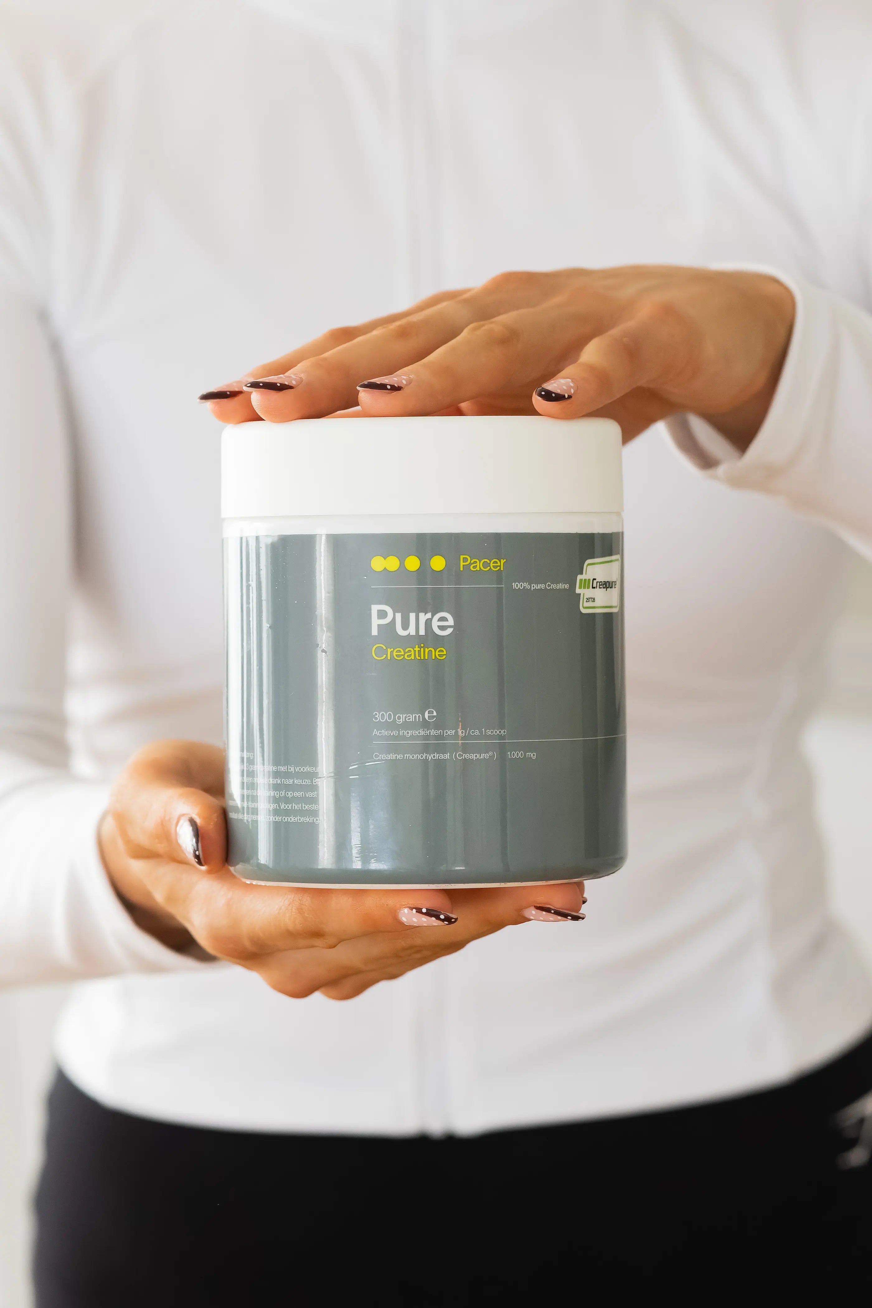 Pot PACER PURE creatine 300g met Creapure® wordt vastgehouden door sporter