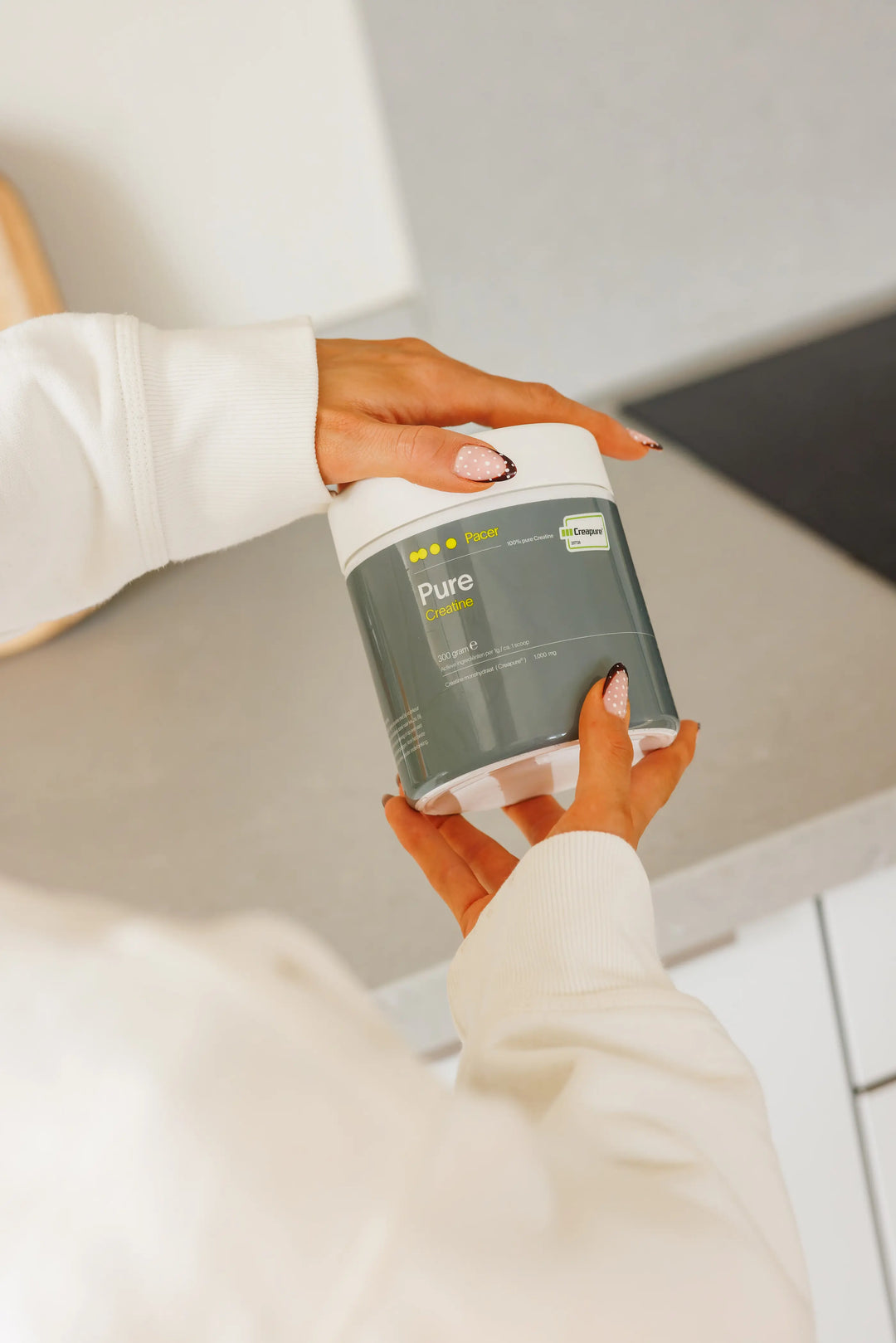 Sporter houdt PACER PURE creatine vast en bekijkt het label in de keuken